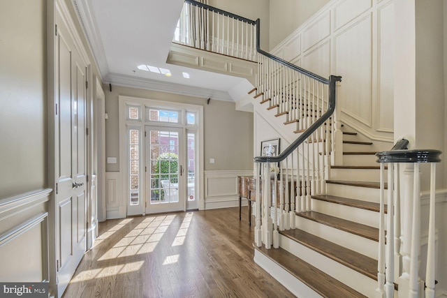 entrance foyer featuring stairs, crown molding, wood finished floors, and a decorative wall