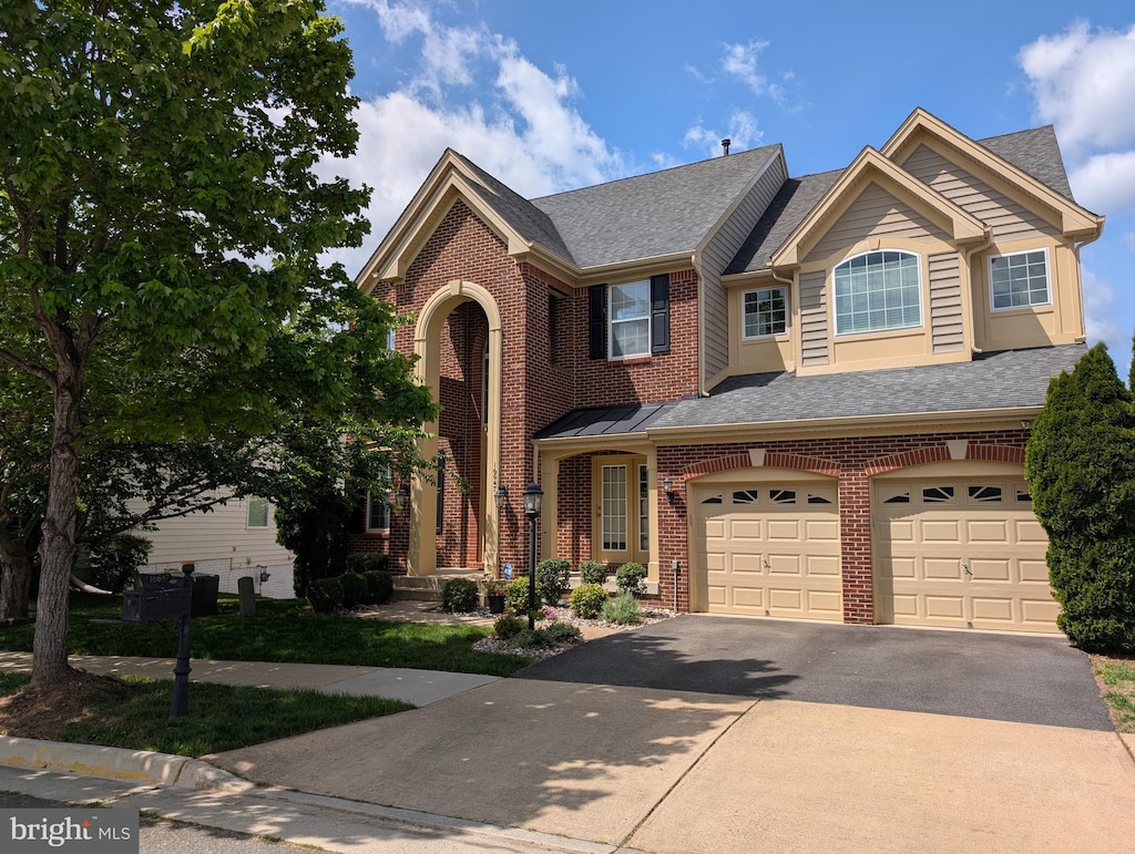 traditional-style home featuring brick siding, aphalt driveway, an attached garage, and roof with shingles