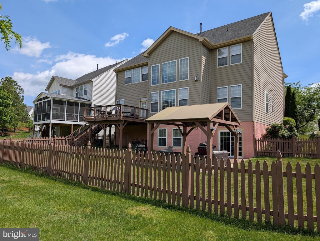 rear view of property with a fenced backyard, a sunroom, a gazebo, a yard, and stairway