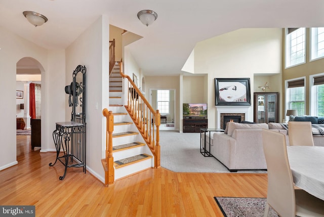 16647 Space More Cir, Woodbridge, VA 22191 - stairway with arched walkways, wood finished floors, baseboards, a glass covered fireplace, and a high ceiling