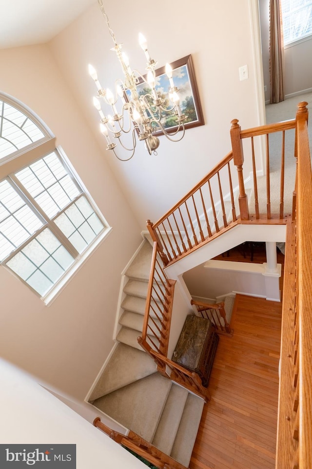 staircase with a notable chandelier and wood finished floors
