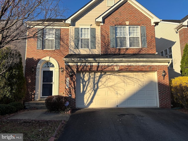 traditional home with aphalt driveway, a garage, and brick siding