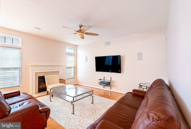 living room featuring visible vents, a high end fireplace, wood finished floors, and a ceiling fan