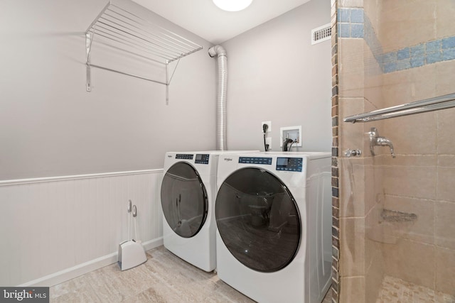 washroom featuring laundry area, washing machine and dryer, light wood-type flooring, and visible vents
