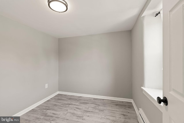 unfurnished room featuring baseboards, baseboard heating, and light wood finished floors