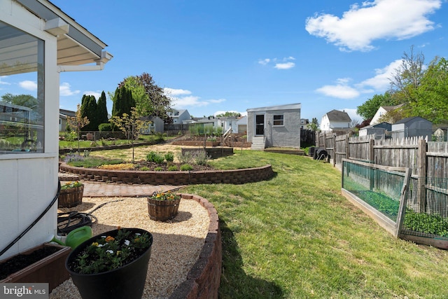view of yard featuring an outbuilding, a residential view, a fenced backyard, and a vegetable garden