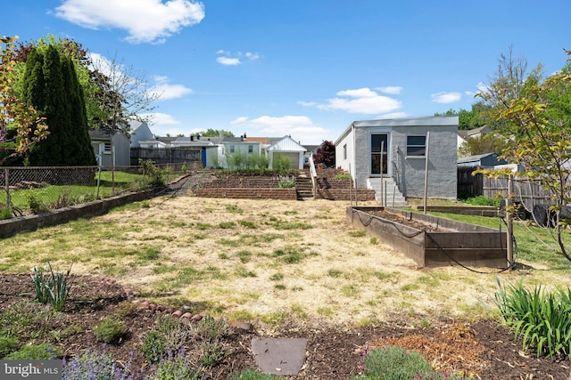 view of yard with an outdoor structure, a garden, and a fenced backyard
