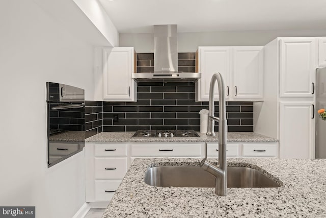 kitchen featuring exhaust hood, stainless steel appliances, white cabinetry, and a sink