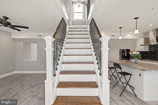 staircase with visible vents, ceiling fan, and wood finished floors