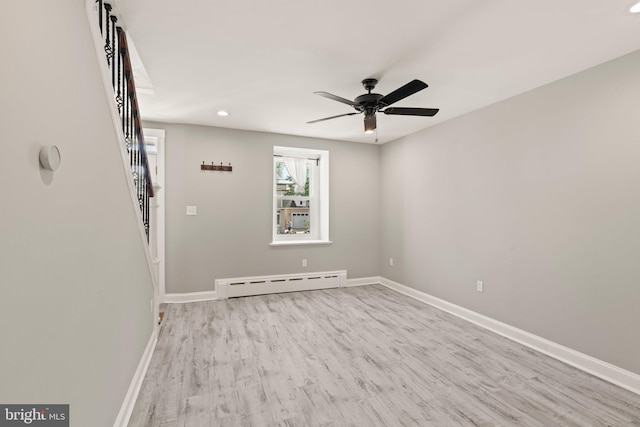 spare room with wood finished floors, baseboards, ceiling fan, stairway, and a baseboard radiator