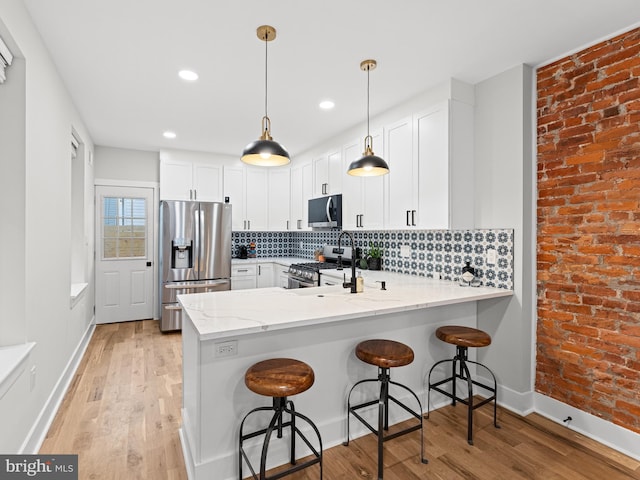 1611 N Dover St, Philadelphia, PA 19121 - kitchen featuring light wood-type flooring, light stone counters, decorative backsplash, a peninsula, and stainless steel appliances