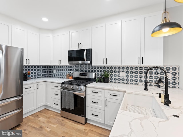 1611 N Dover St, Philadelphia, PA 19121 - kitchen with decorative backsplash, stainless steel appliances, light wood-style floors, white cabinetry, and a sink