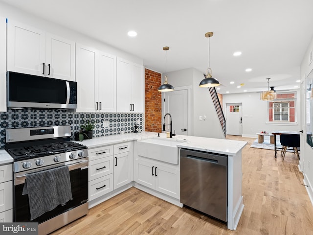 1611 N Dover St, Philadelphia, PA 19121 - kitchen featuring a sink, light wood-style floors, appliances with stainless steel finishes, a peninsula, and decorative backsplash