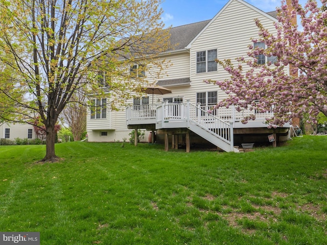 back of house with a deck, a lawn, and a shingled roof