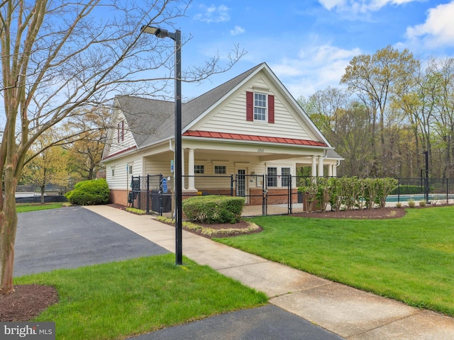 view of front of home with brick siding, a gate, a standing seam roof, and asphalt driveway