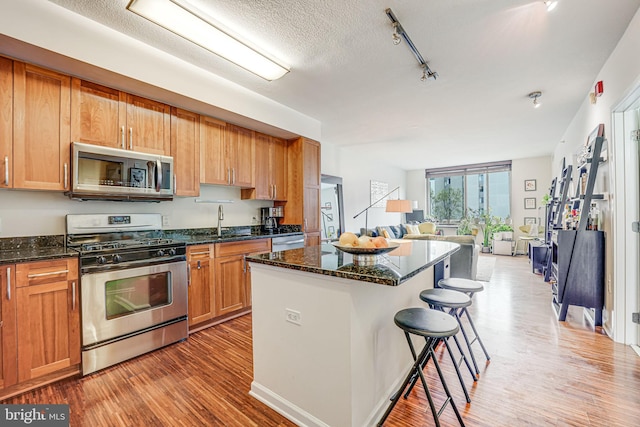 440 L St NW Unit 513, Washington, DC 20001 - kitchen featuring light wood finished floors, a center island, a sink, open floor plan, and appliances with stainless steel finishes