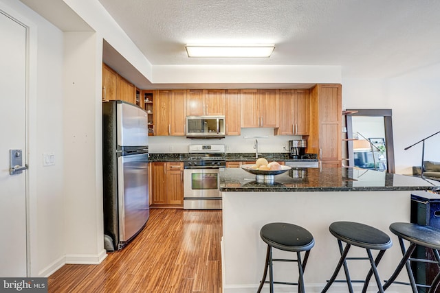440 L St NW Unit 513, Washington, DC 20001 - kitchen with light wood finished floors, a kitchen breakfast bar, a sink, baseboards, and appliances with stainless steel finishes