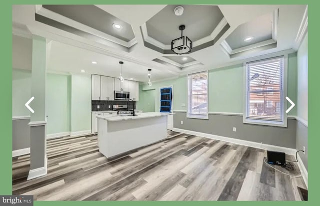 kitchen featuring stainless steel microwave, tasteful backsplash, white cabinets, and crown molding