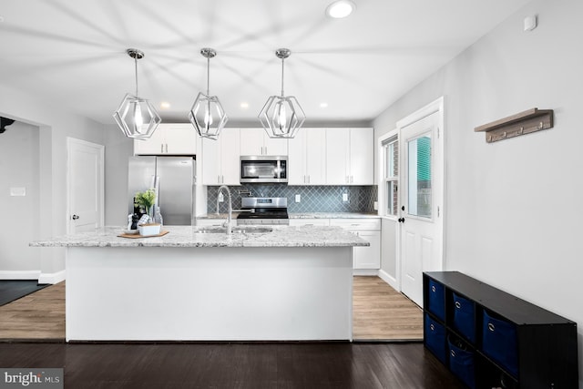 kitchen with dark wood-type flooring, a sink, backsplash, white cabinetry, and stainless steel appliances