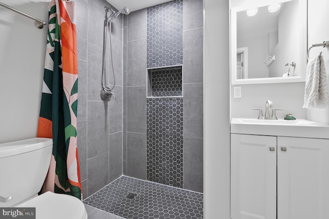 bathroom featuring vanity, toilet, and tiled shower