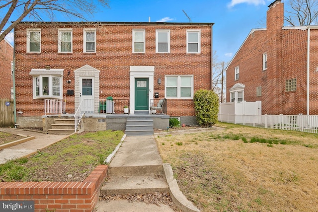 view of front of property with brick siding, a front yard, and fence
