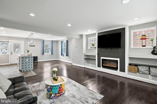 living area with recessed lighting, baseboards, a large fireplace, and dark wood-style flooring