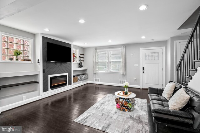 living area featuring visible vents, stairs, baseboards, and wood finished floors