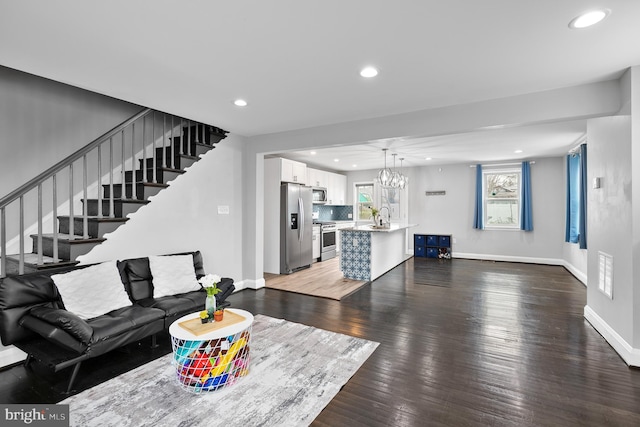 living room featuring stairway, baseboards, an inviting chandelier, recessed lighting, and light wood-type flooring