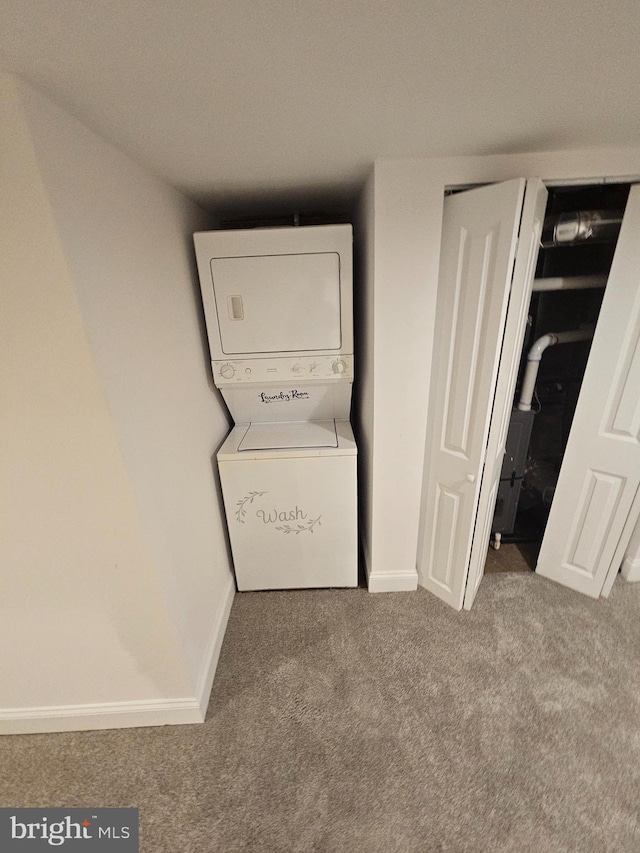 clothes washing area featuring stacked washer / drying machine, carpet flooring, baseboards, and laundry area