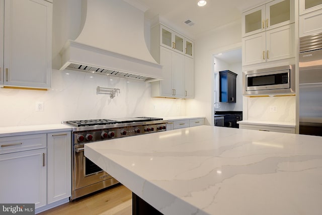 2762A Bon Haven Ln, Annapolis, MD 21401 - kitchen with tasteful backsplash, built in appliances, light stone counters, premium range hood, and light wood-style floors