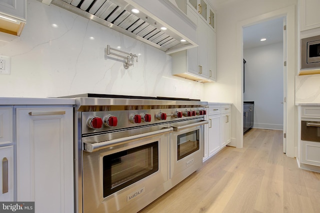 2762A Bon Haven Ln, Annapolis, MD 21401 - kitchen with custom exhaust hood, glass insert cabinets, white cabinets, light wood-style floors, and appliances with stainless steel finishes