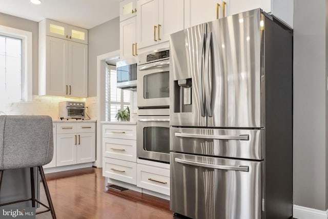 kitchen featuring dark wood finished floors, white cabinetry, tasteful backsplash, and appliances with stainless steel finishes