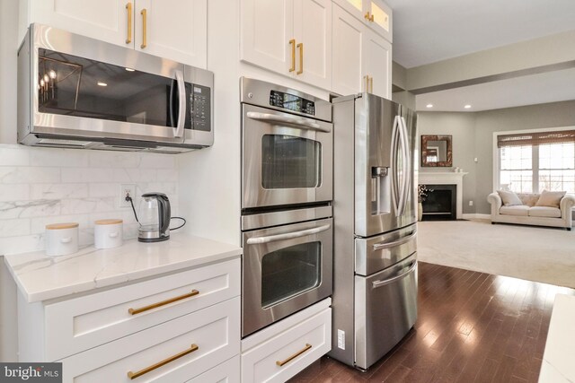 kitchen featuring white cabinetry, open floor plan, tasteful backsplash, and appliances with stainless steel finishes