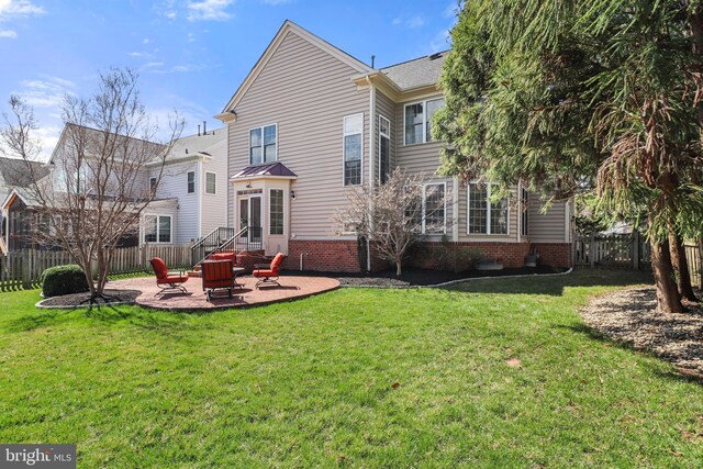 rear view of house with a fenced backyard, a yard, and a patio area