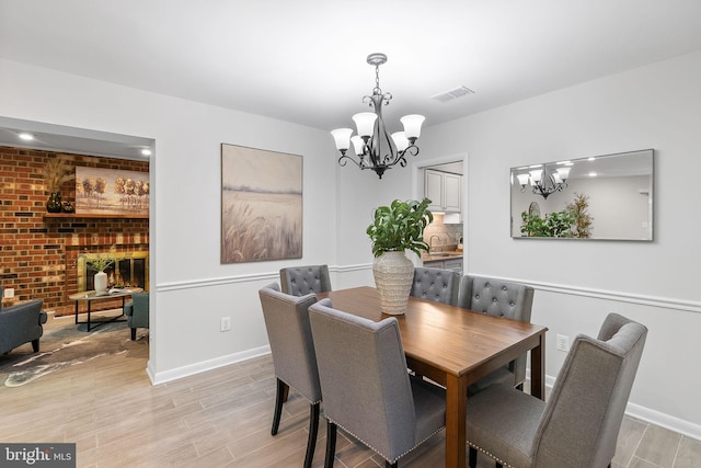 dining room featuring baseboards, visible vents, light wood-type flooring, and a chandelier