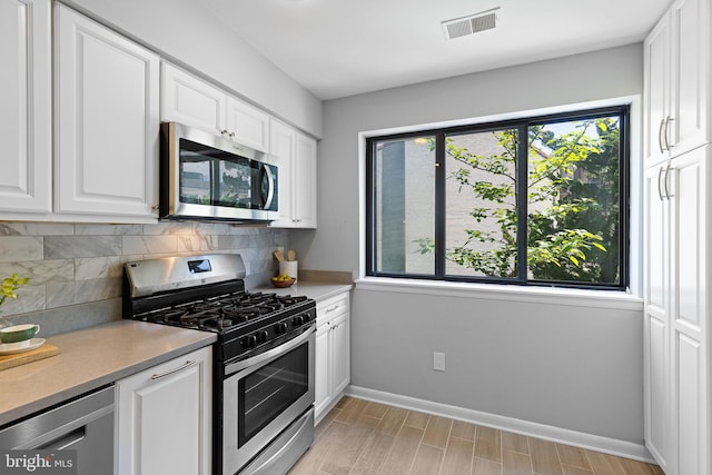 kitchen with baseboards, decorative backsplash, a wealth of natural light, and stainless steel appliances