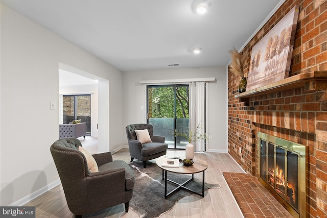 living room with a brick fireplace, baseboards, visible vents, and wood finished floors