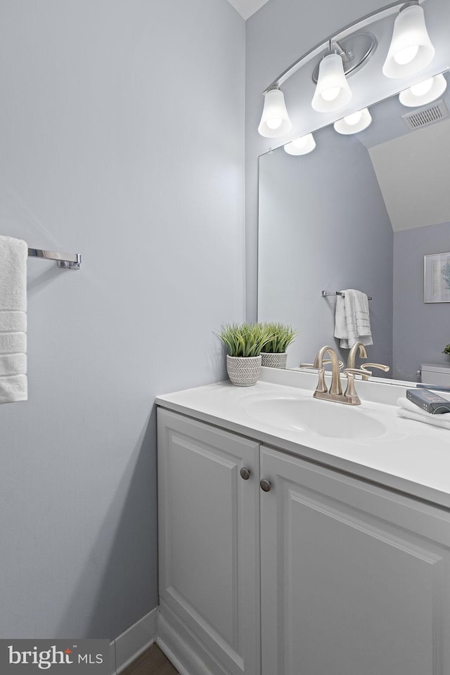 bathroom featuring visible vents, vaulted ceiling, and vanity