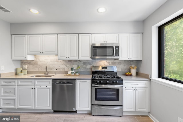 kitchen with white cabinetry, appliances with stainless steel finishes, a wealth of natural light, and a sink