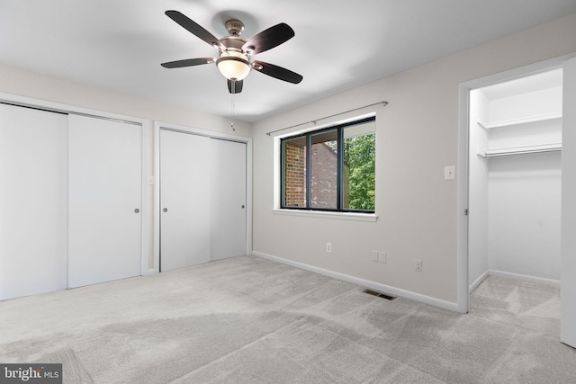 unfurnished bedroom featuring ceiling fan, multiple closets, carpet, baseboards, and visible vents