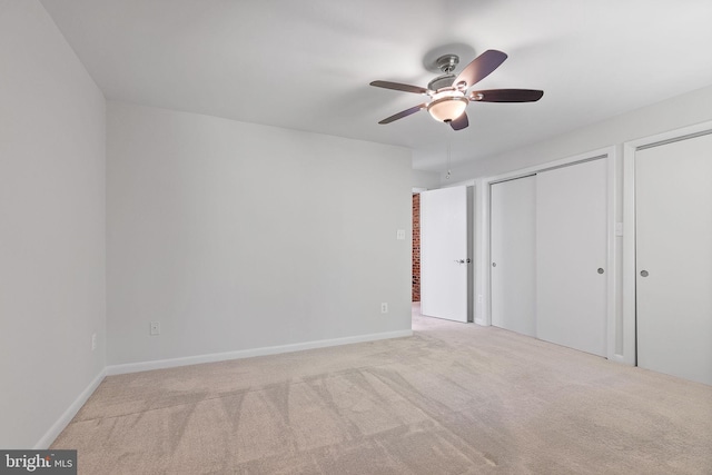 unfurnished bedroom with a ceiling fan, baseboards, carpet, and two closets