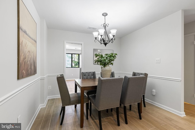 dining area with light wood-style floors, baseboards, a notable chandelier, and visible vents