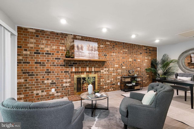living room featuring a fireplace, recessed lighting, and brick wall