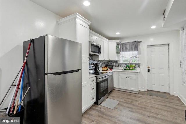 1557 N 9th St, Philadelphia, PA 19122 - kitchen with white cabinetry, recessed lighting, stainless steel appliances, light wood finished floors, and backsplash