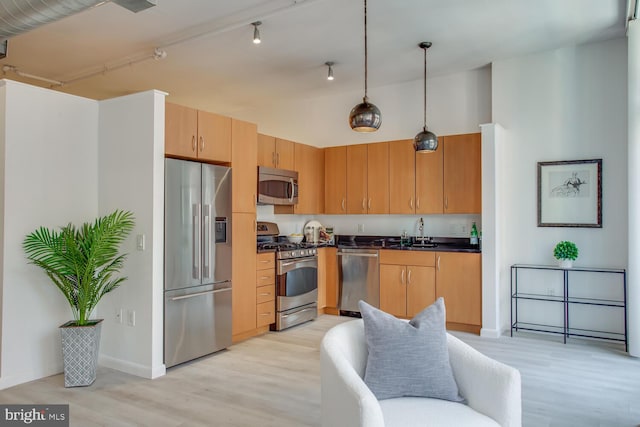 811 4th St NW Unit 608, Washington, DC 20001 - kitchen featuring appliances with stainless steel finishes, dark countertops, light wood-style floors, a sink, and pendant lighting