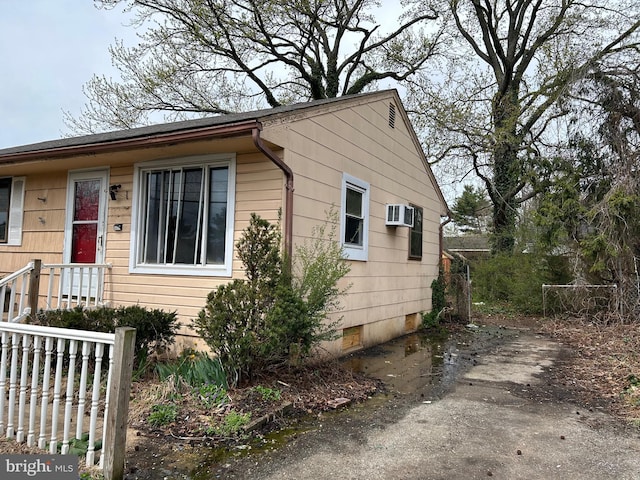 exterior space featuring crawl space, fence, and an AC wall unit