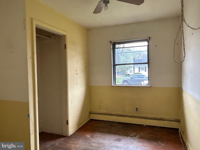 unfurnished bedroom featuring wood finished floors, a baseboard heating unit, and ceiling fan