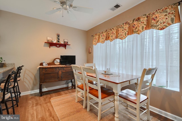 dining room with wood finished floors, a ceiling fan, and baseboards