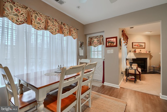 dining space featuring wood finished floors, baseboards, and a fireplace with flush hearth