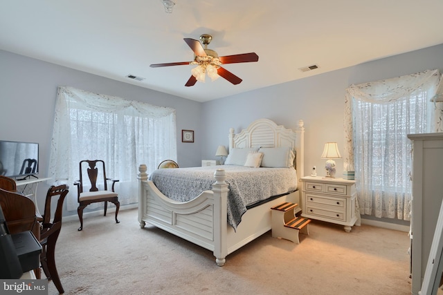 bedroom featuring light carpet, a ceiling fan, and baseboards